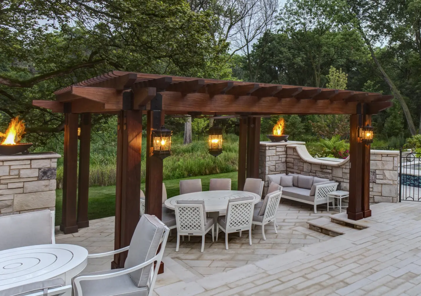 08 tropical hardwood ipe pergola with glowing lanterns and gas fire bowls above Valders stone patio